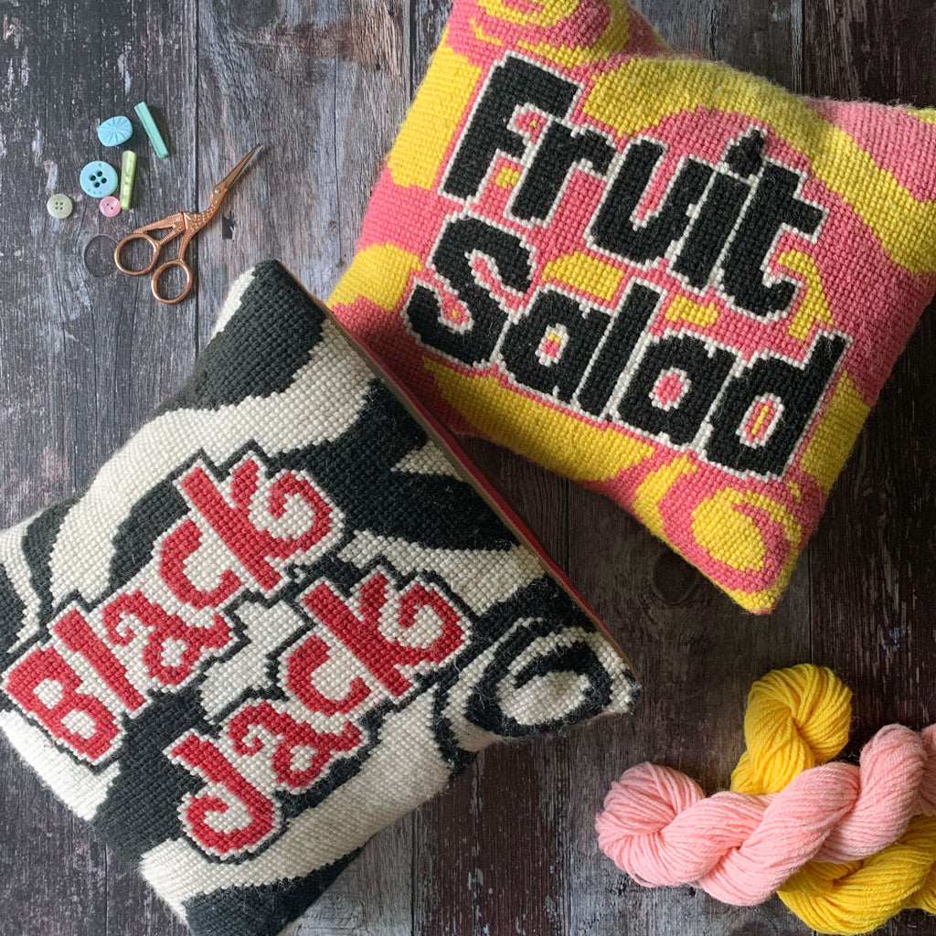 wool supersize tuck tapestry cross stitch items with text on a wooden surface with yarn and scissors.